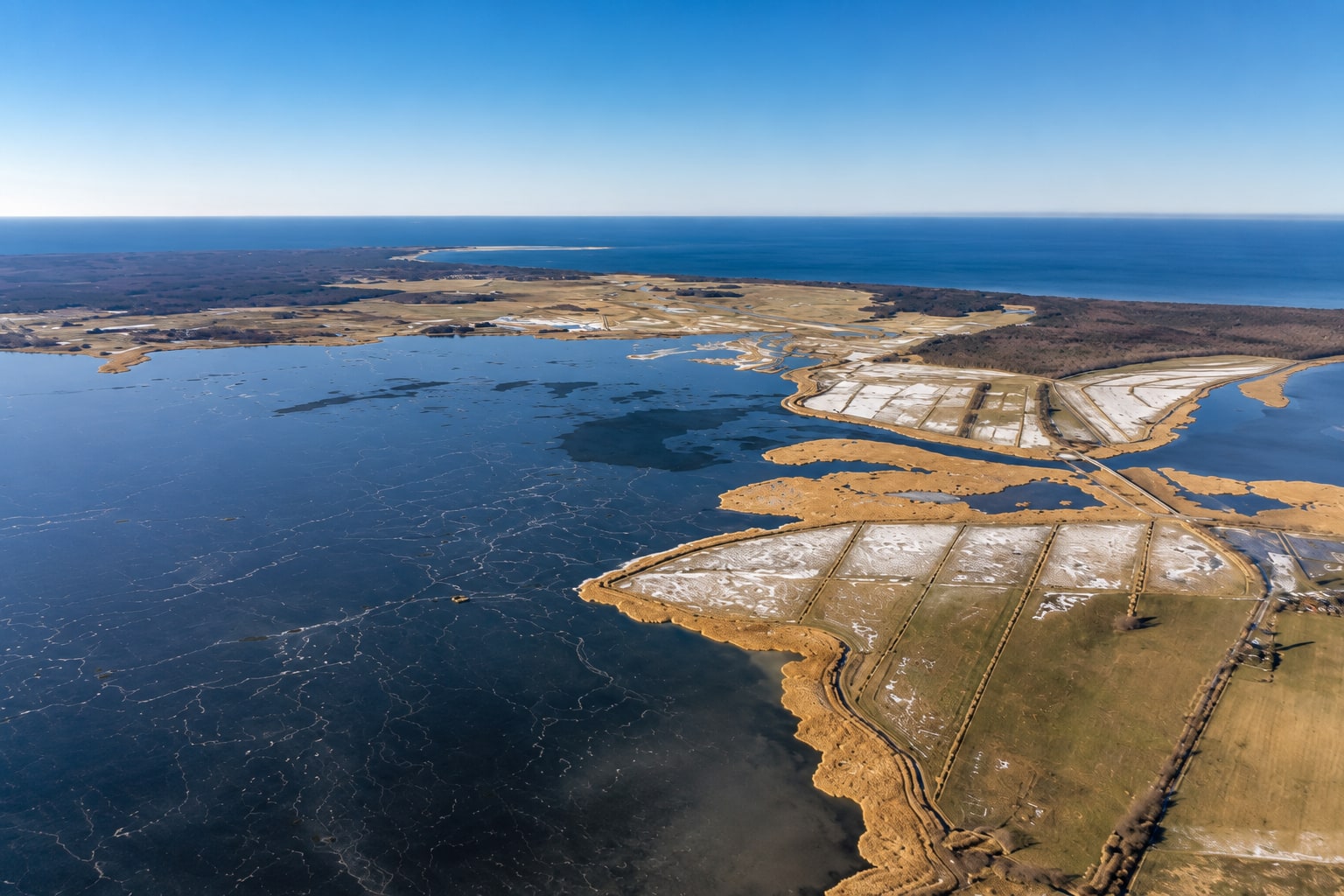 Luftbild der Boddenlandschaft bei Dierhagen: Wasserflächen, Schilfkanten und dahinter die Ostsee