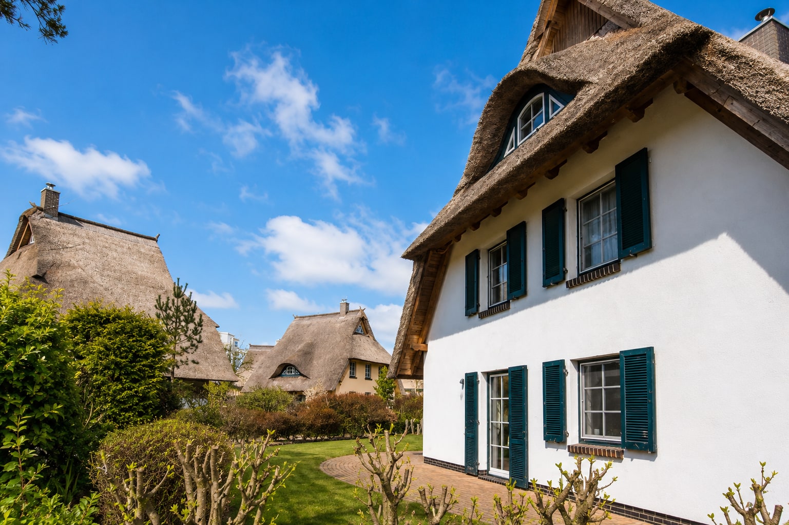 Reetgedecktes Haus mit grünen Fensterläden im Ortskern von Dierhagen Dorf