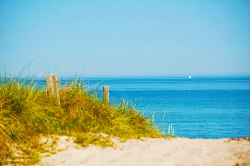 Weiter Sandstrand der Ostsee in Dierhagen mit Dünen und Segelboot am Horizont
